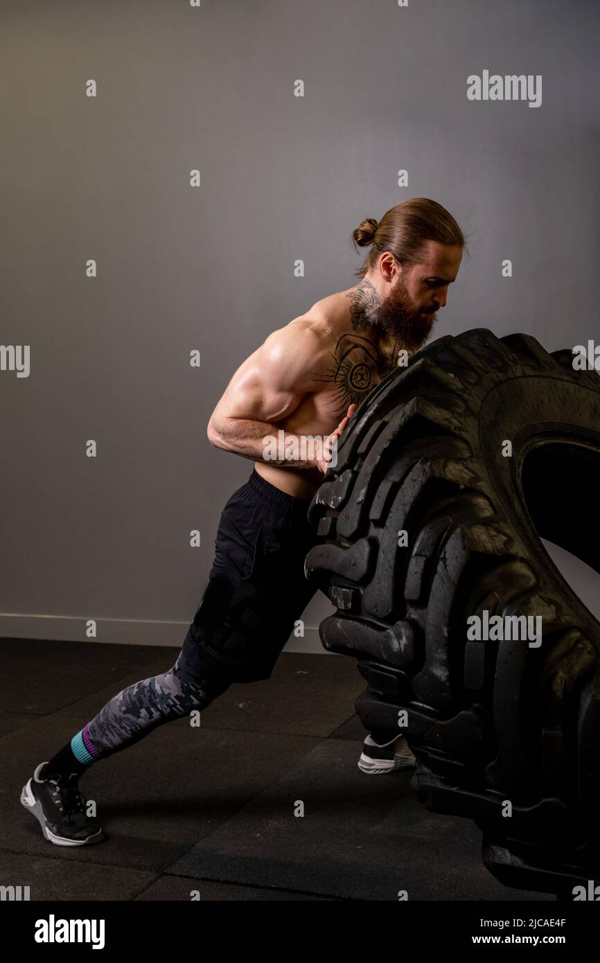 Fitness training tire man wheel flipping fit lifestyle young healthy, from dedication weight in heavy from strength workout, picking cross. Active Stock Photo