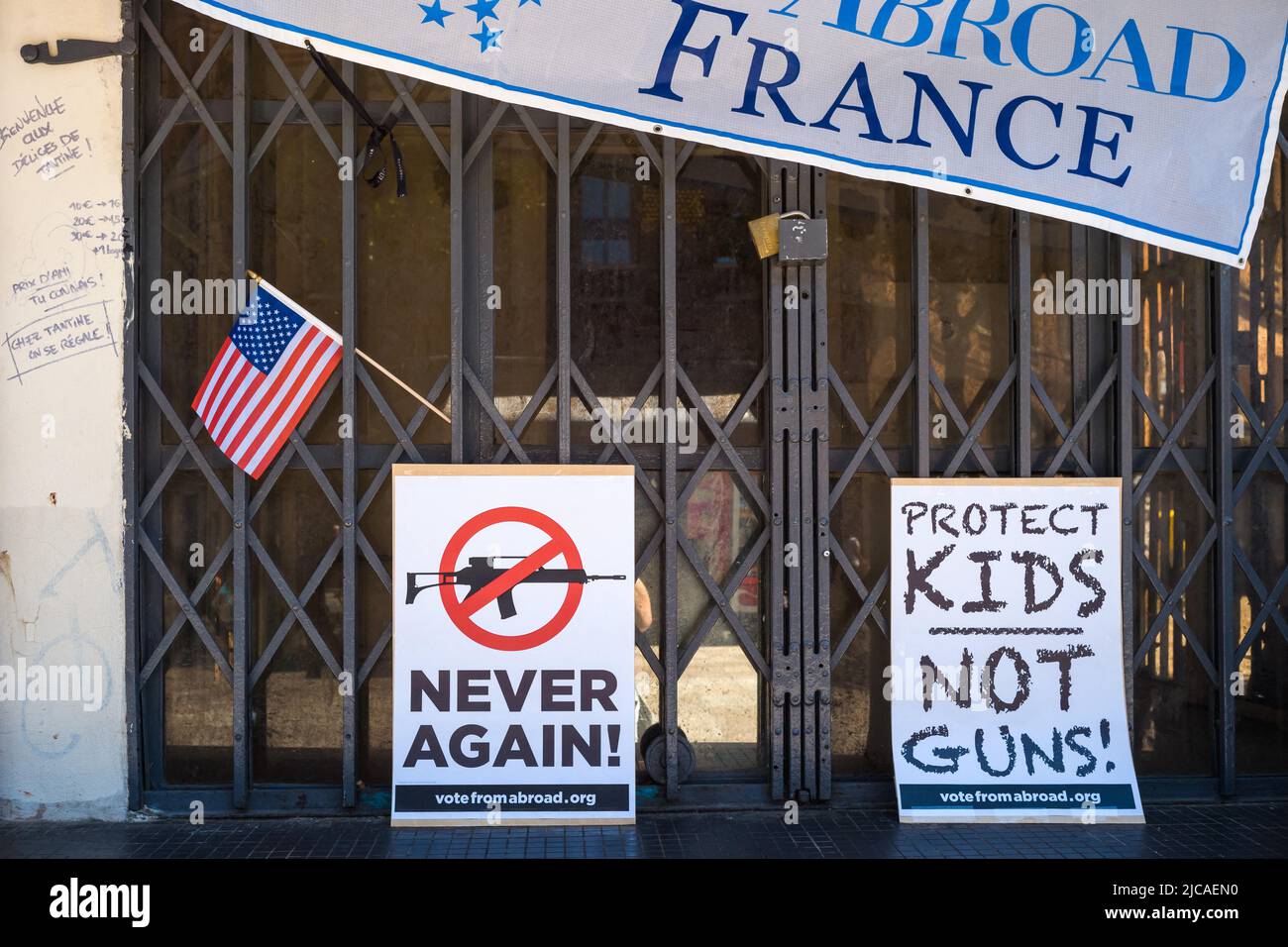 A small American flag, a poster, Never Again! With a forbidden weapon and another poster with the inscription, Protect Kids, not Guns!. Democratic Party rally abroad to honor the victims of the Robb Elementary School killing in Uvalde, Texas on May 24, 2022. France, Toulouse le 11 Juin 2022. Photo by Patricia Huchot-Boissier/ABACAPRESS.COM Stock Photo