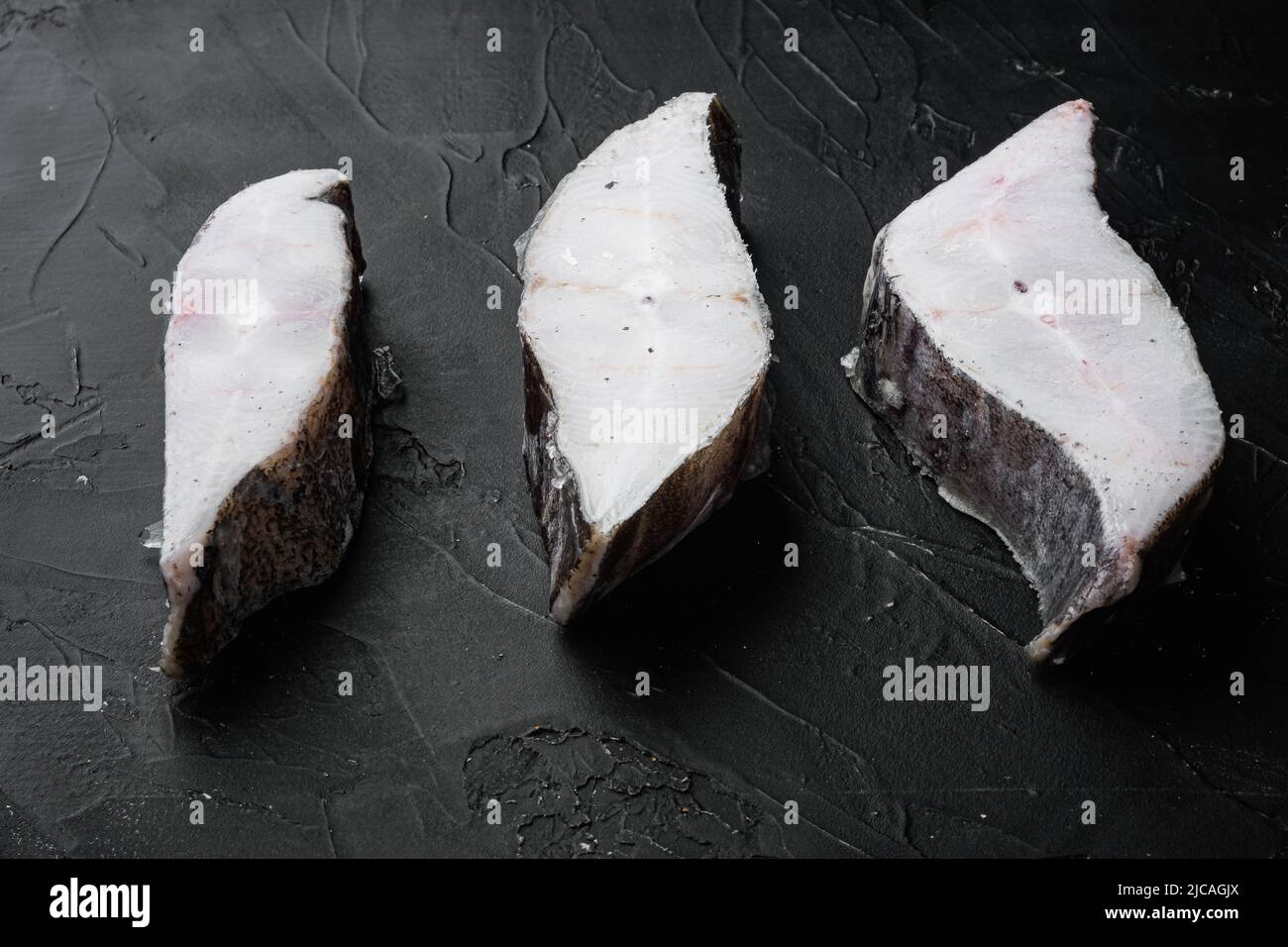 Halibut fish frozen steak, on black dark stone table background Stock ...