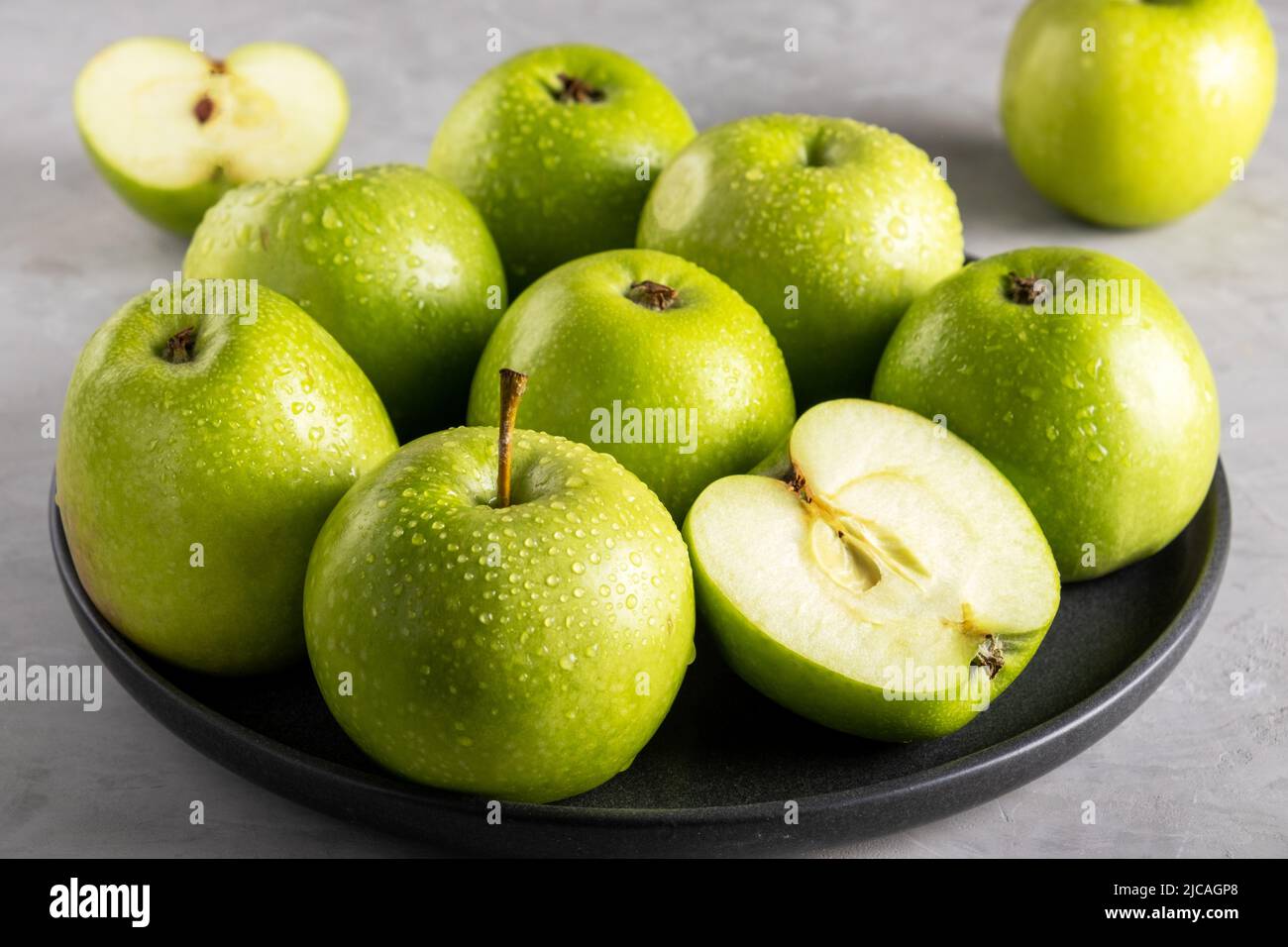 Fresh ripe green apples on a black ceramic plate Stock Photo