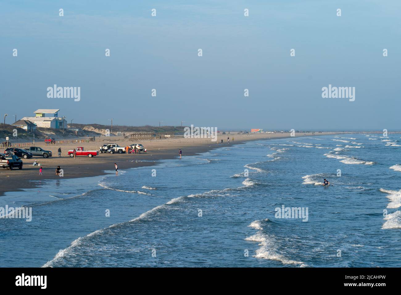 PORT ARANSAS, TX - 17 FEB 2020: Families and tourists enjoying the beach on a hazy evening at the Gulf of Mexico in Texas. Cars and pickup trucks are Stock Photo