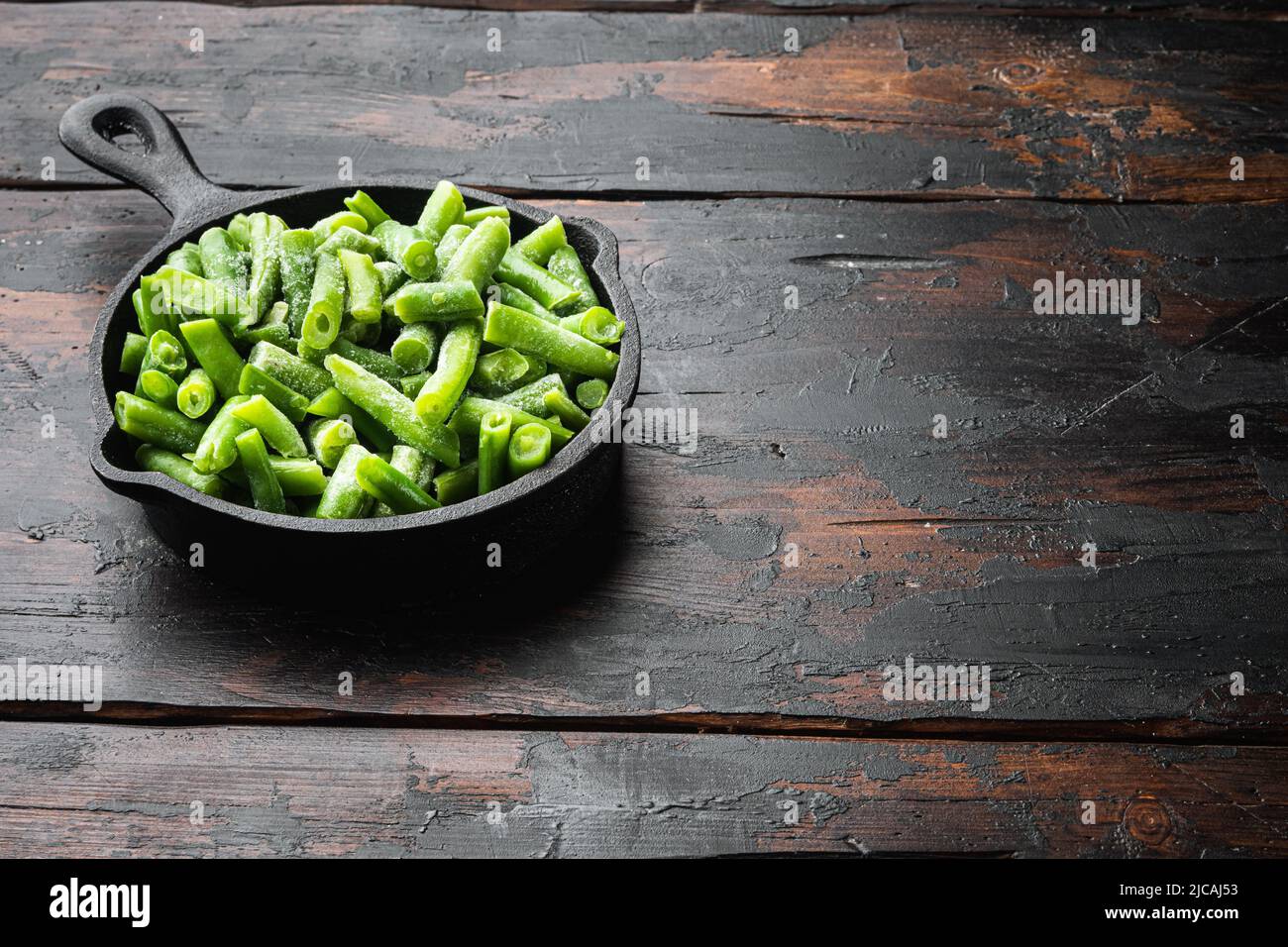 Frozen organic green beans. Healthy food concept set, in frying cast iron pan, on old dark