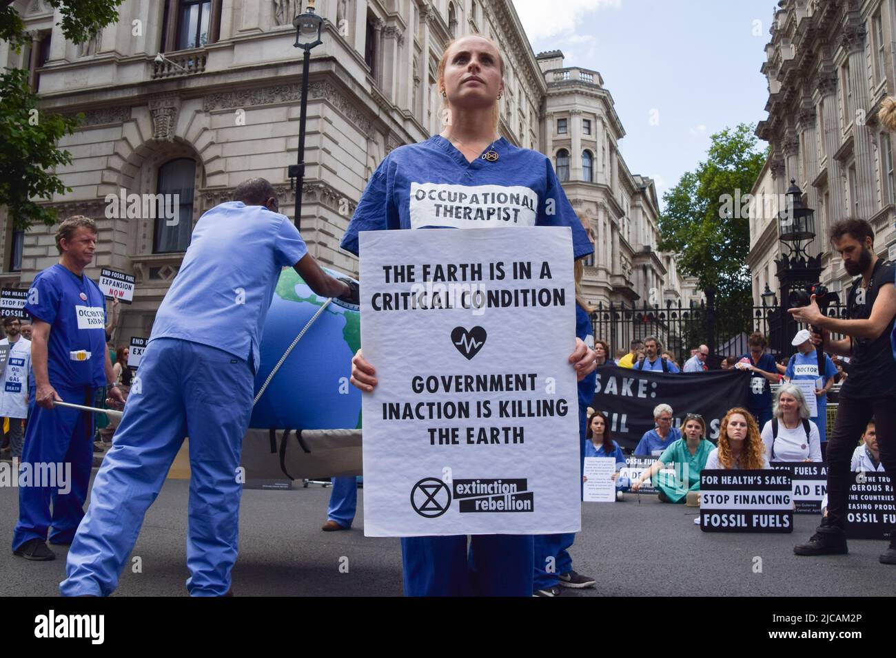 London, UK. 11th June, 2022. A protester holds a placard which says 'Government inaction is killing the Earth' during the demonstration outside Downing Street. Extinction Rebellion doctors, nurses and other health professionals gathered for a protest in Westminster to demand an end to fossil fuel investments. (Photo by Vuk Valcic/SOPA Images/Sipa USA) Credit: Sipa USA/Alamy Live News Stock Photo