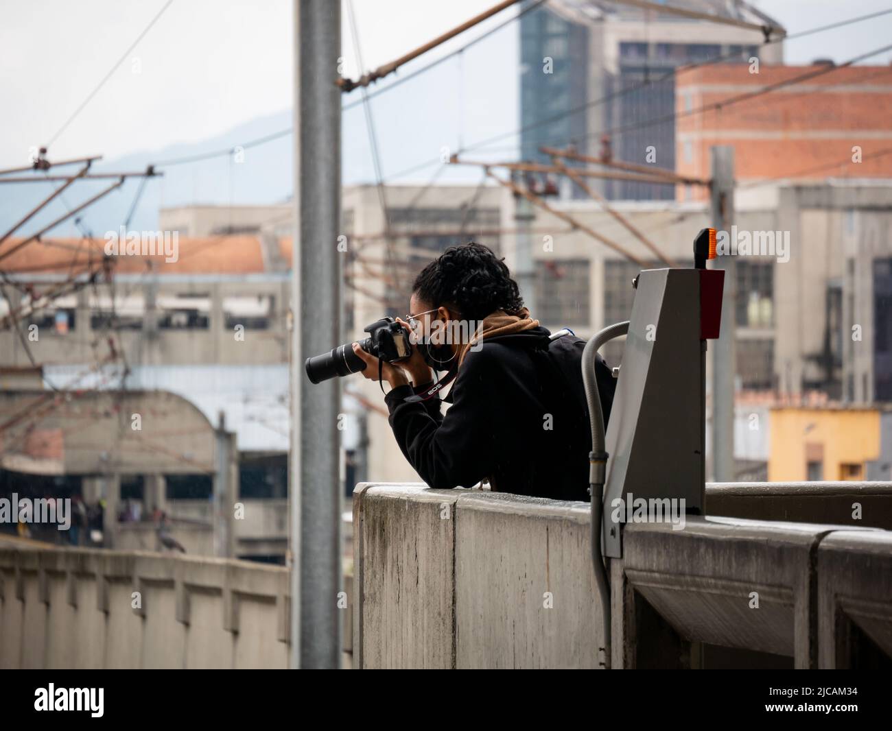 Medellin, Antioquia, Colombia - March 6 2022: Colombian Woman with Black Hair Wears a Black Mask, Big Earrings and Glasses Takes Pictures with her Cam Stock Photo