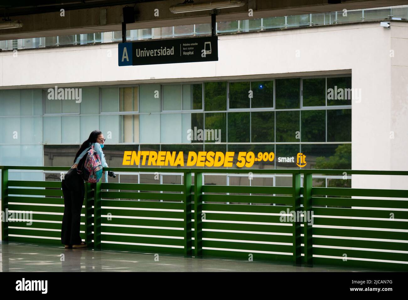 Medellin, Antioquia, Colombia - March 6 2022: Colombian Woman Leaning on a Green Balcony with a View of the Sign that says: 'Work Out at the Gym from Stock Photo