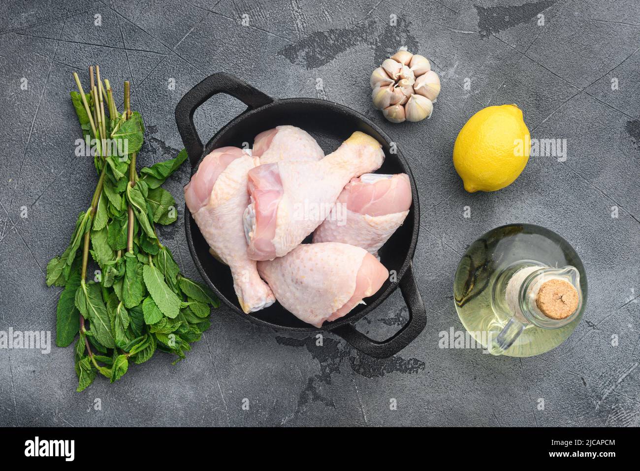 Raw marinated chicken meat, chicken legs set, on frying cast iron pan