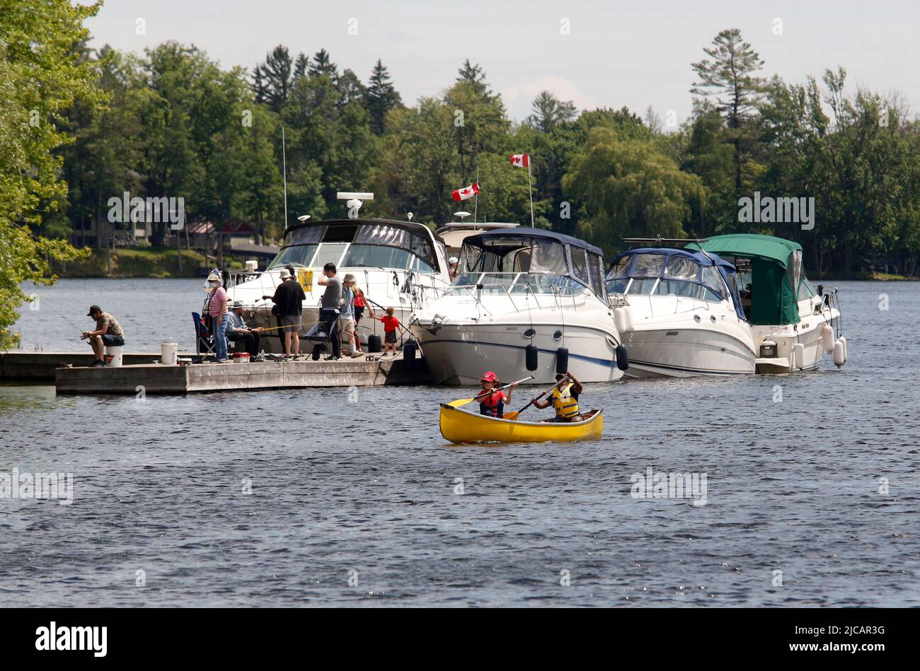 People canoe past boats on the Rideau Canal in Ottawa on Saturday, June