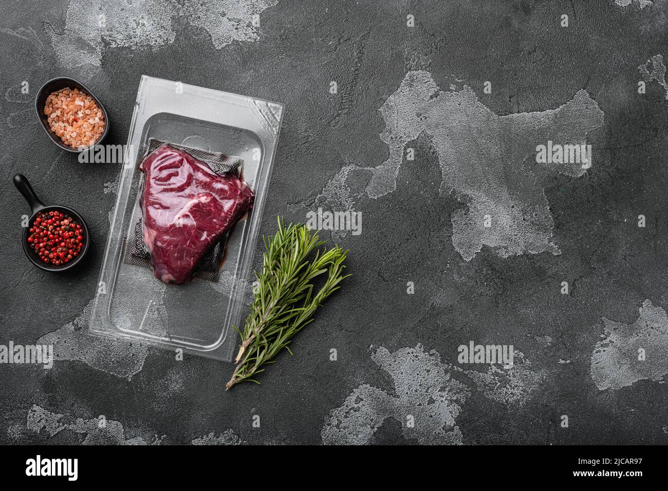 Market pack with raw rump beef steak, on black dark stone table ...