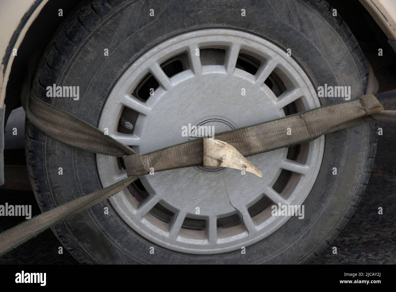 Straps tightly fastened to the tire of a car on a tow truck. Stock Photo