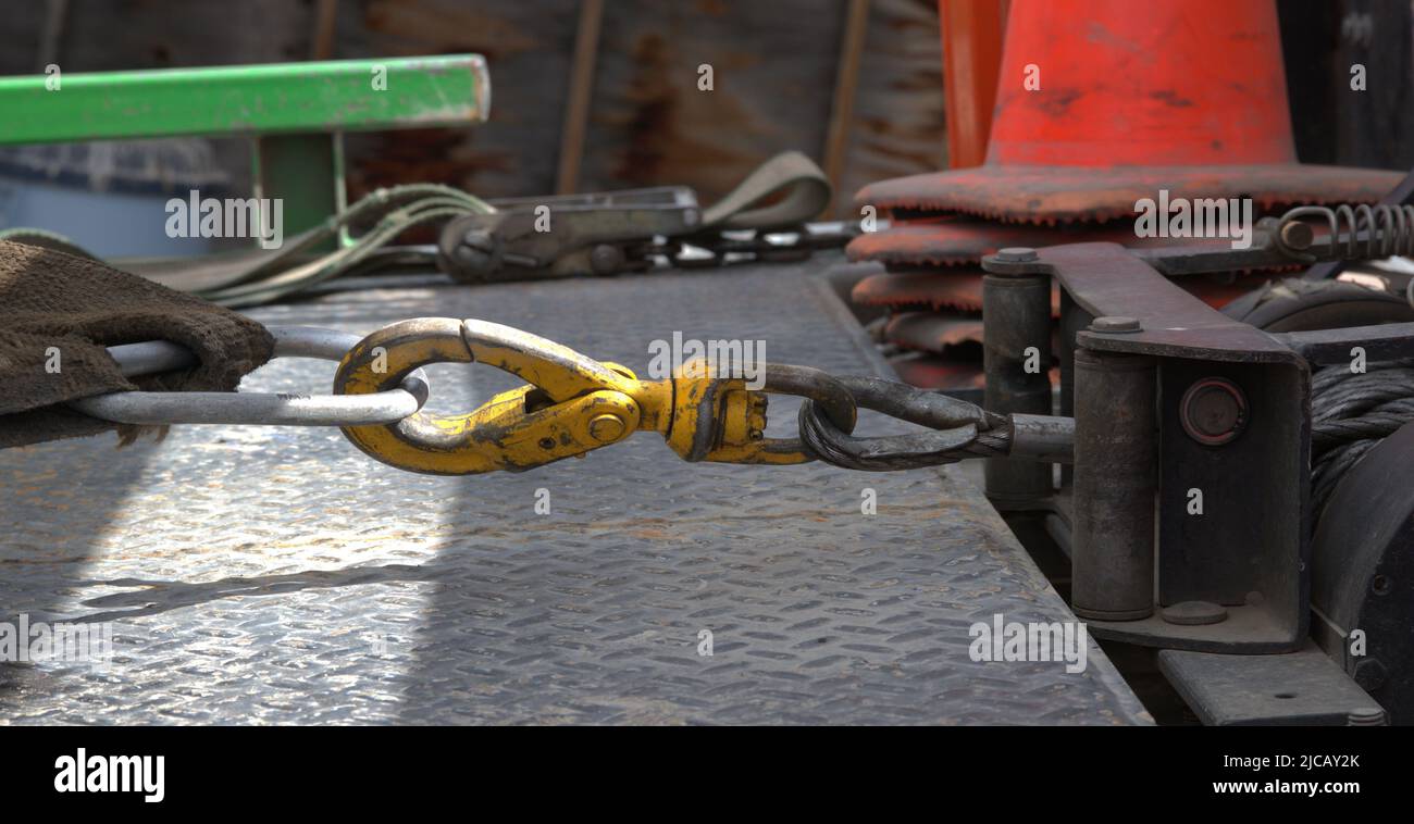 Connection of a tow truck winch to the cable attached to an automobile on the truck bed. Stock Photo