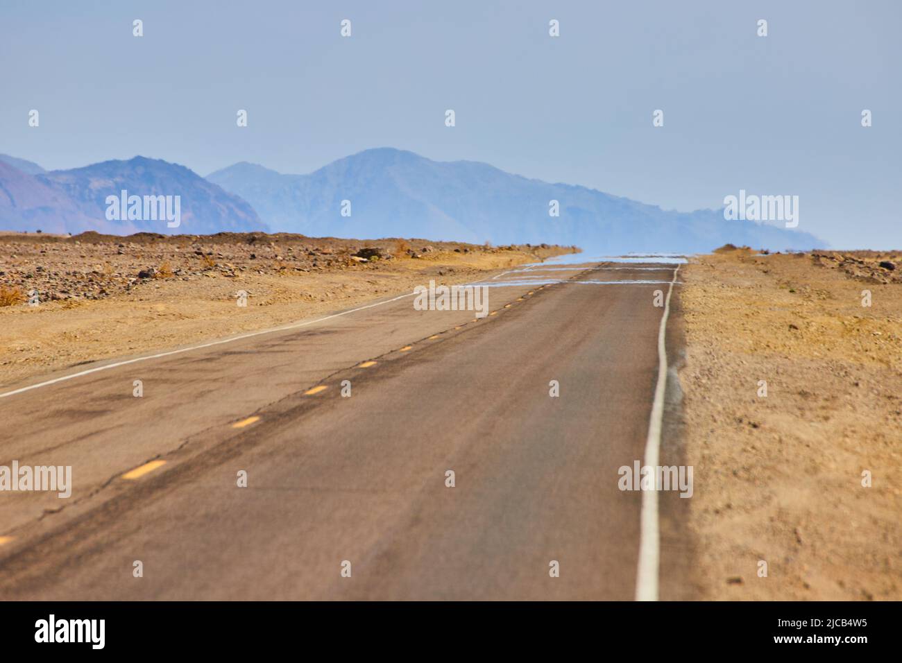 Mirage on road in desert landscape with mountains Stock Photo - Alamy