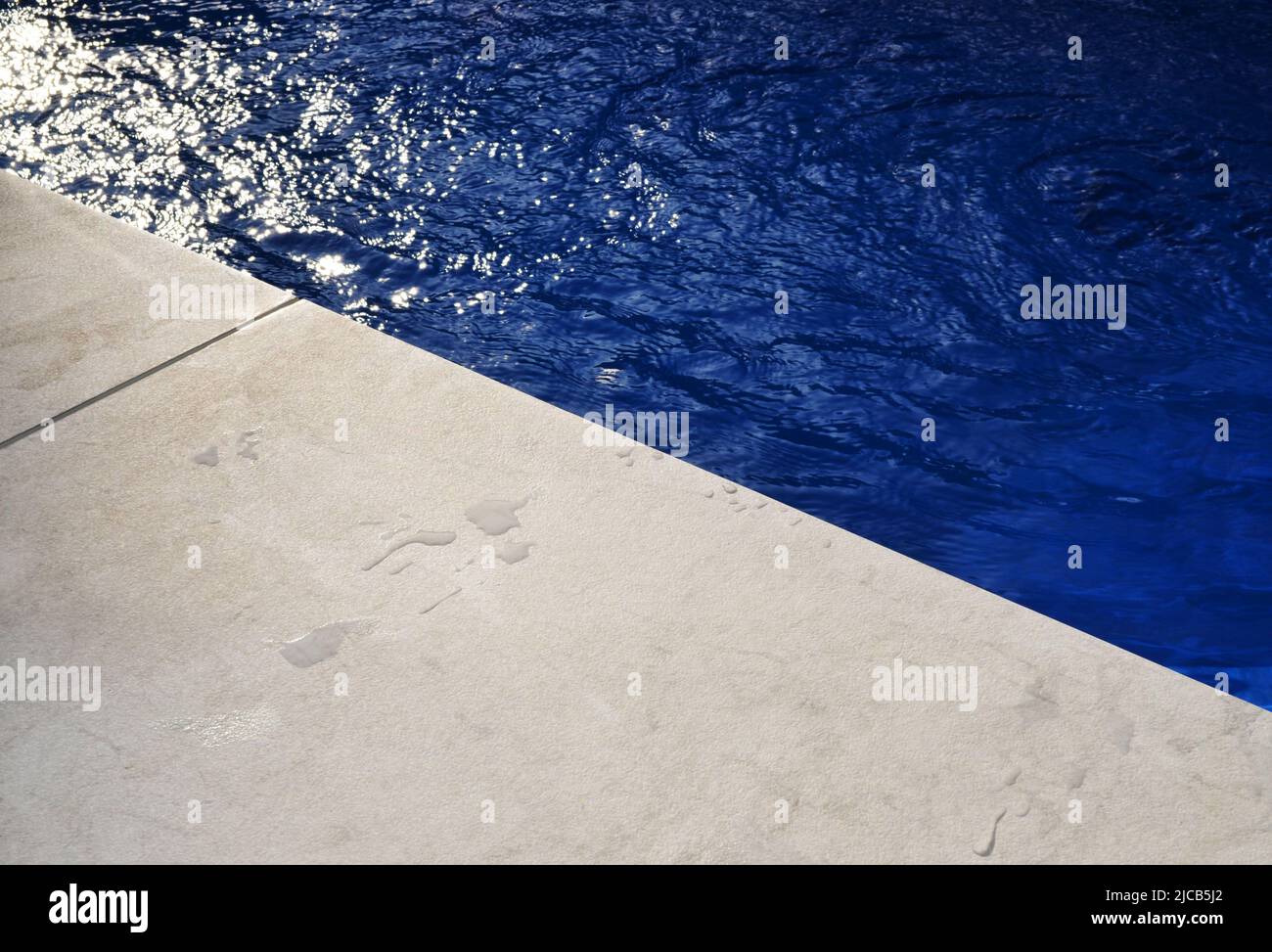 Edge of swimming pool blue water grey paving Stock Photo