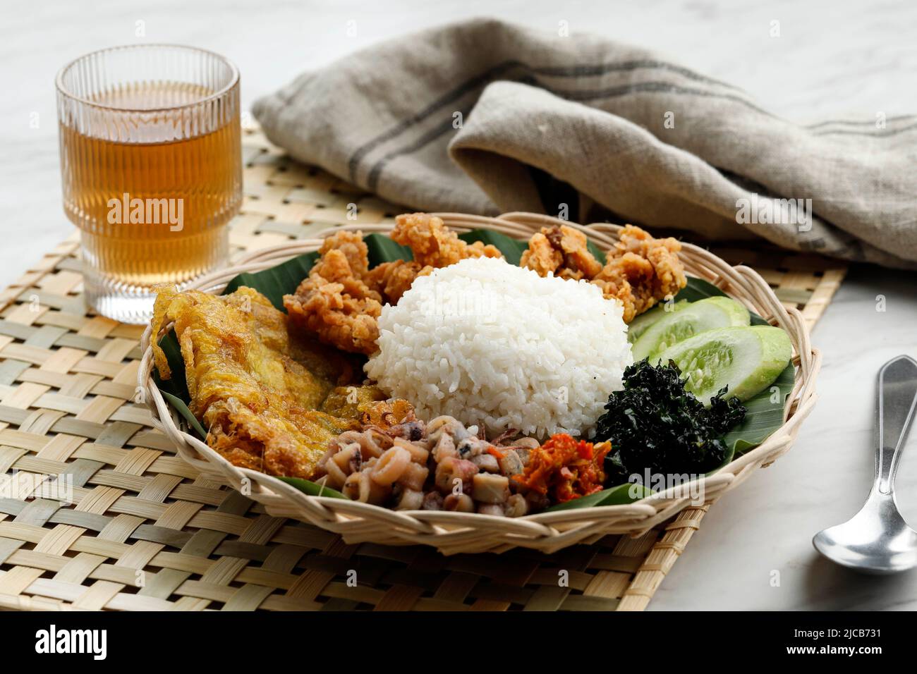 Selected Focus Nasi Campur Cumi Asin, White Rice with Sautee Salted Squid, Sambal, Egg, Kulit Ayam Crispy Chicken Skin, and Boiled Cassava Leaf. Stock Photo