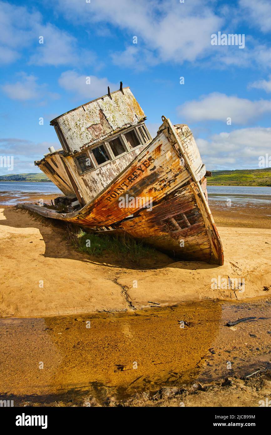 Sandy beach with abandoned shipwreck falling apart Stock Photo