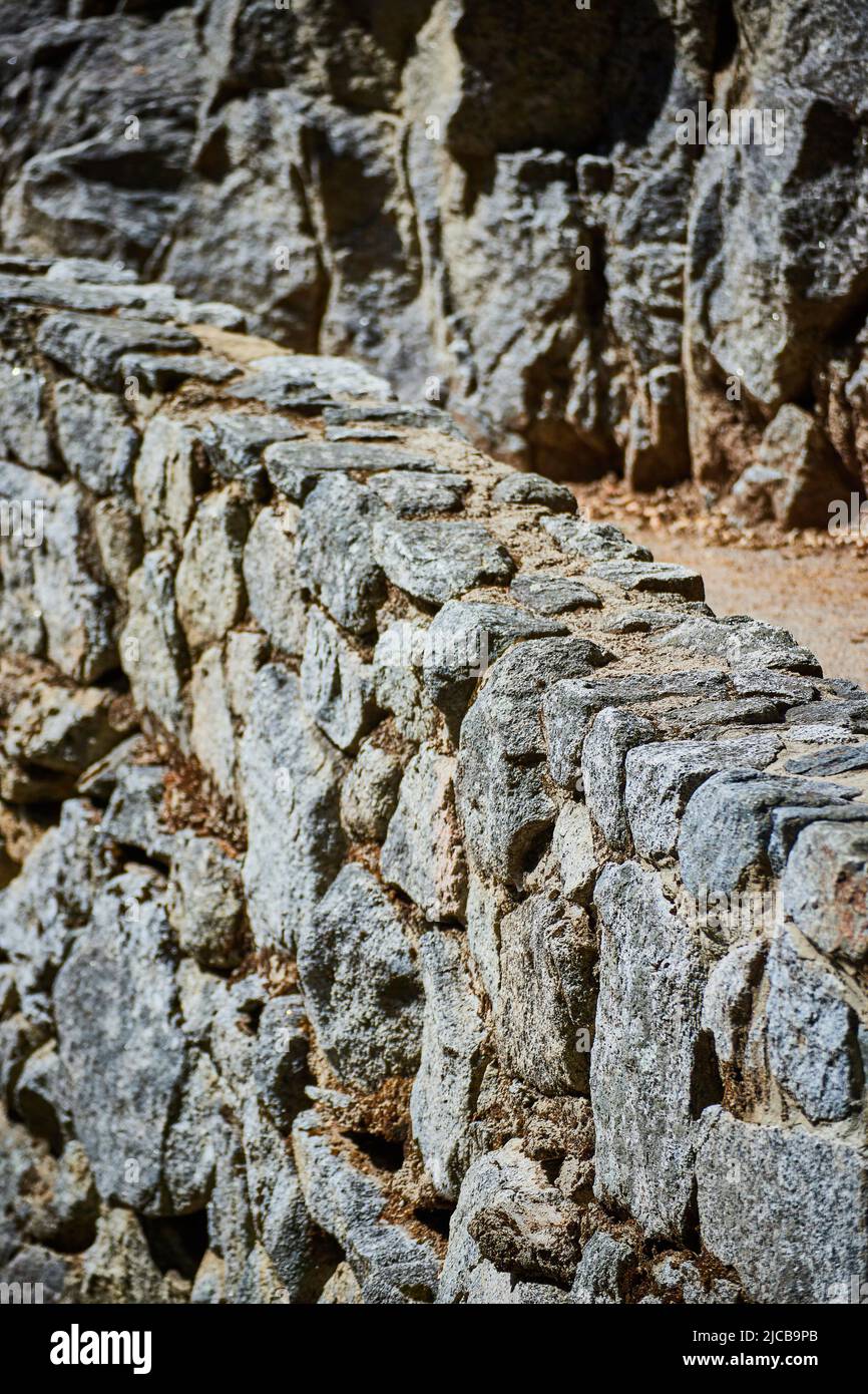 Stone wall next to rocky cliffs and hiking path Stock Photo