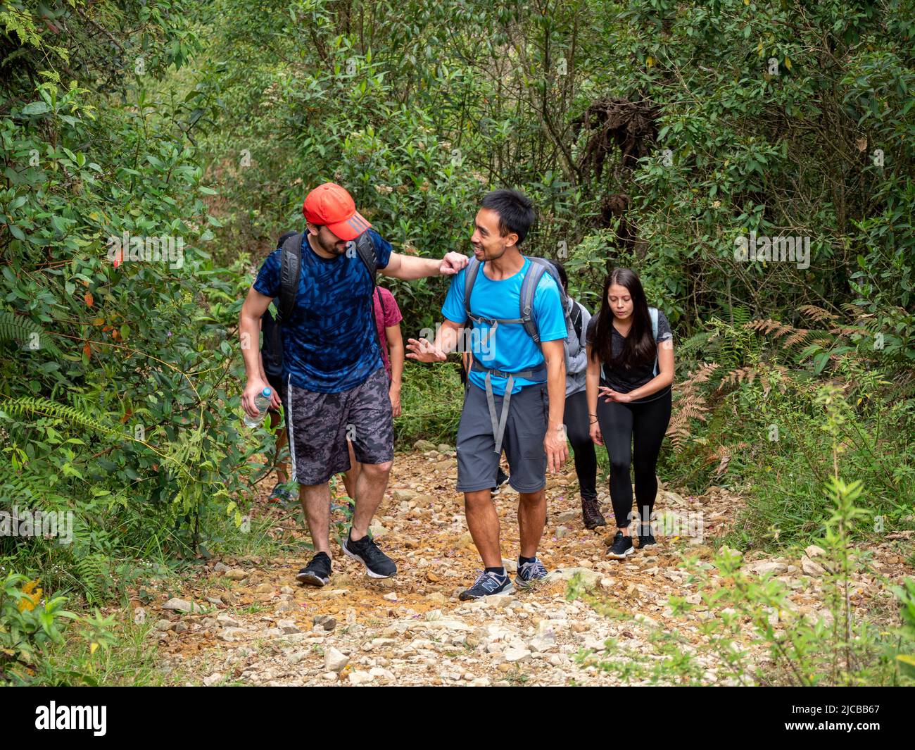 La Estrella, Antioquia, Colombia - February 13 2022: Group of Young People of Different Nationalities Climbing up the Mountain and Smiling at the Came Stock Photo