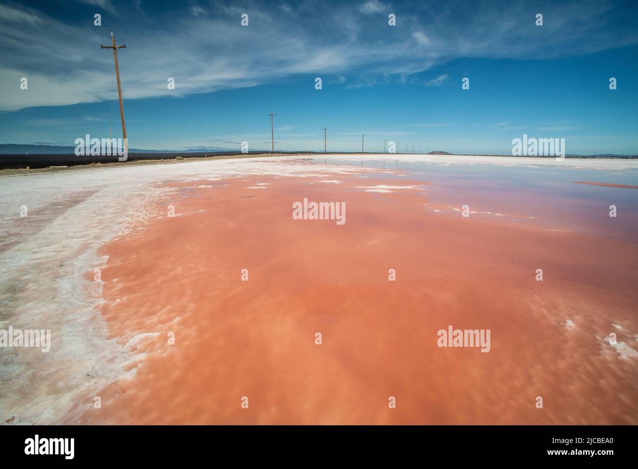 A landscape with Sea salt production ponds with pink water created by salt loving microbes. Stock Photo