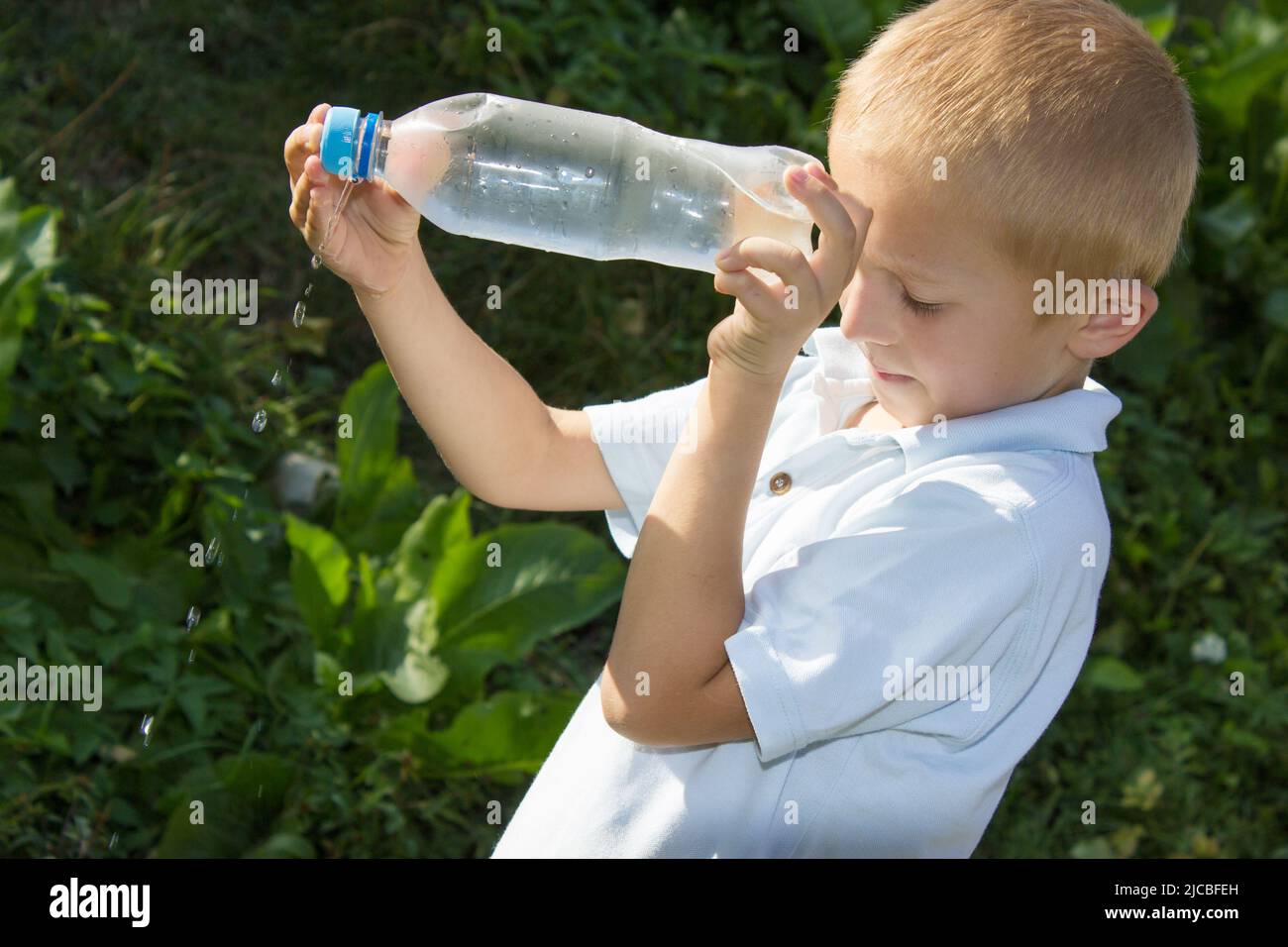 boy raising his bottle of water pouring down Stock Photo Alamy