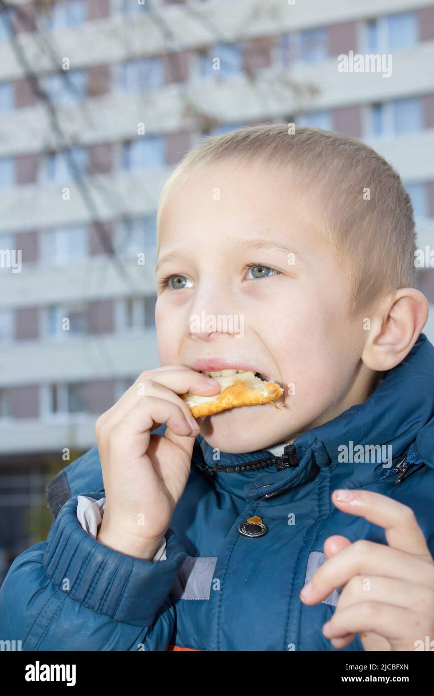 delicious pasties with meat eating boy in city street Stock Photo