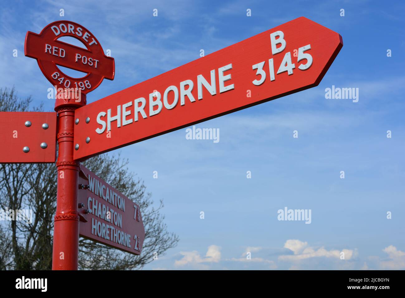 Traditional and distinctive Dorset Red Post, road sign pointing towards Sherborne on the B1345 road near Poyntington Stock Photo