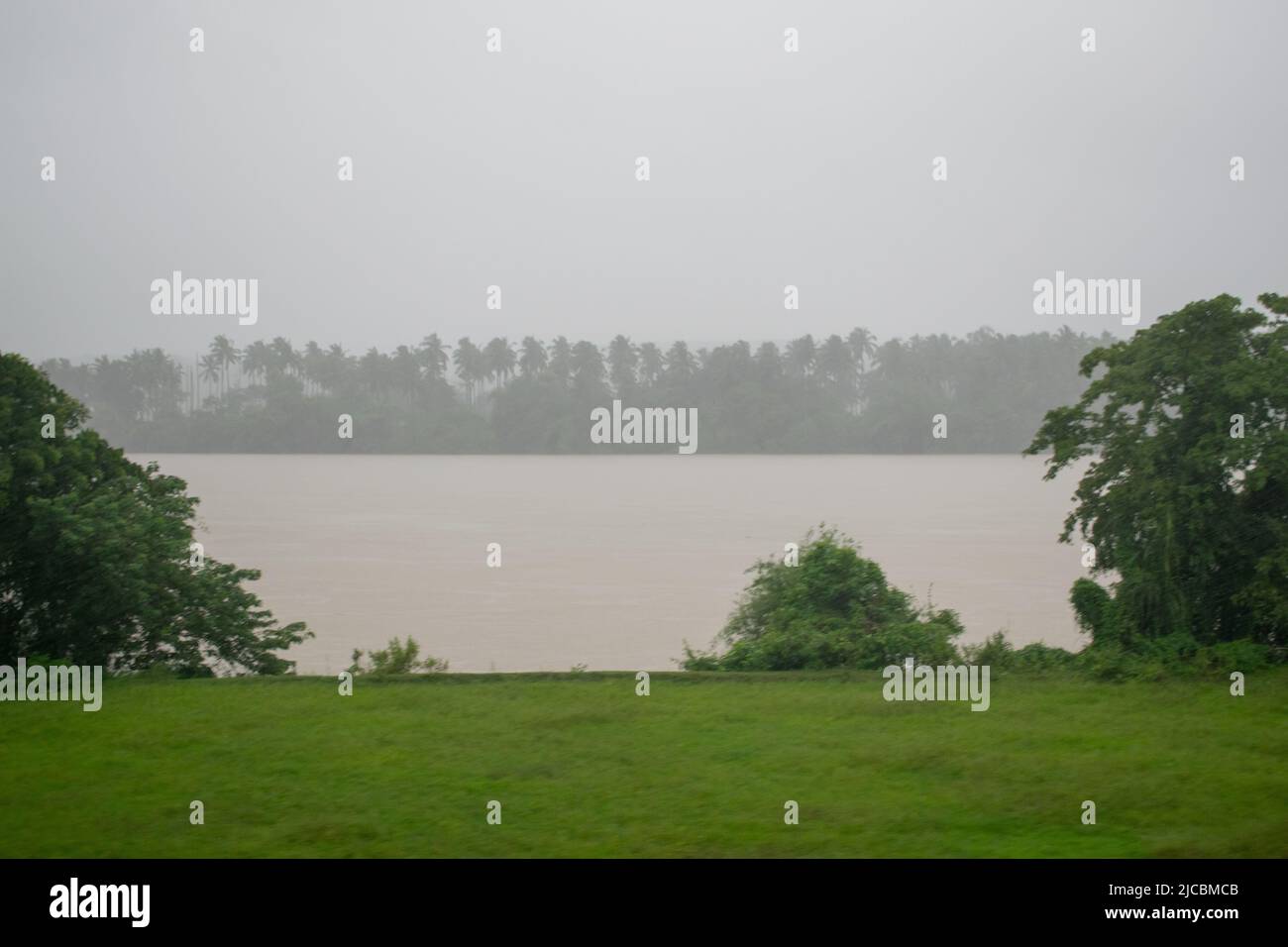 view of a river and it's riverbank during a down pore , pic taken during flood time in India Stock Photo