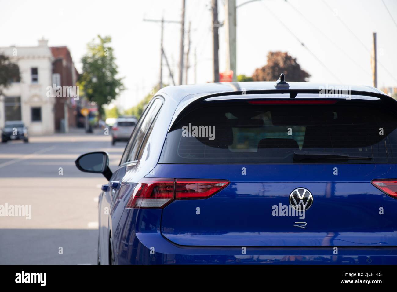 The rear of a blue VW, Volkswagen Golf R is seen while parked on a city street on a sunny afternoon Stock Photo