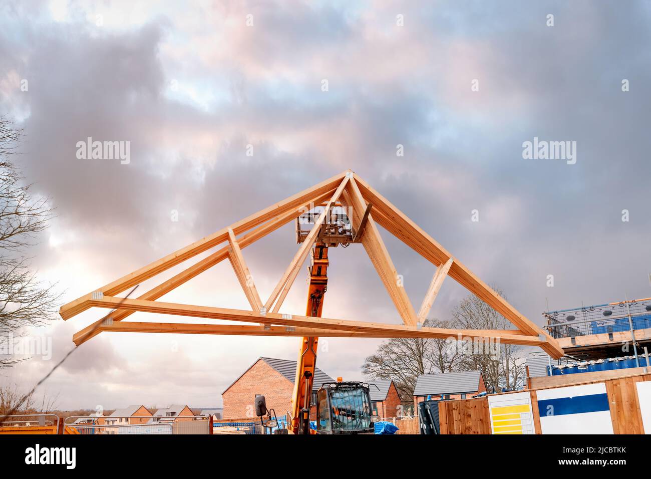 Heavy machinery shifting roof trusses on new residential housing development construction site Stock Photo