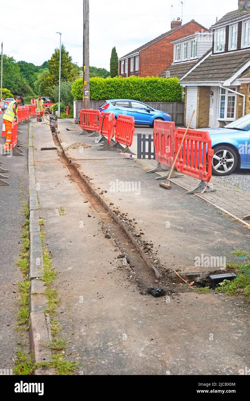 Fibre optic super fast broadband infrastructure project in rural Essex village shallow trench in pavement buried cable & black house connection box UK Stock Photo
