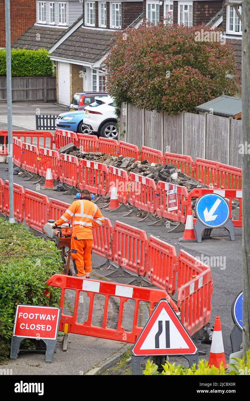 Construction worker compacting backfill in trench hole above new fibre optic broadband cable part of high speed critical technology network UK village Stock Photo