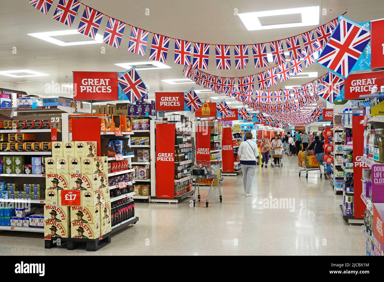 Shoppers & interior view of union jack flags above Sainsburys supermarket shopping isle celebrating  Queen Elizabeth Platinum Jubilee Essex England UK Stock Photo