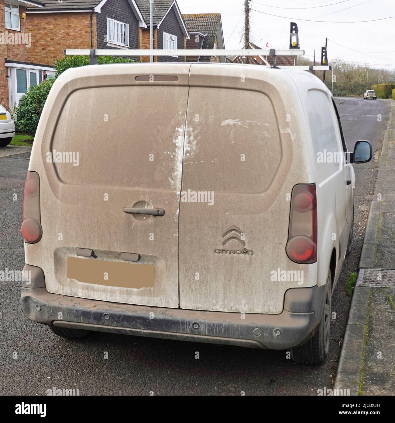 Back view of very dirty parked white Citroen van with obscured number plate otherwise just visible through the road dirt sucked onto the rear doors UK Stock Photo