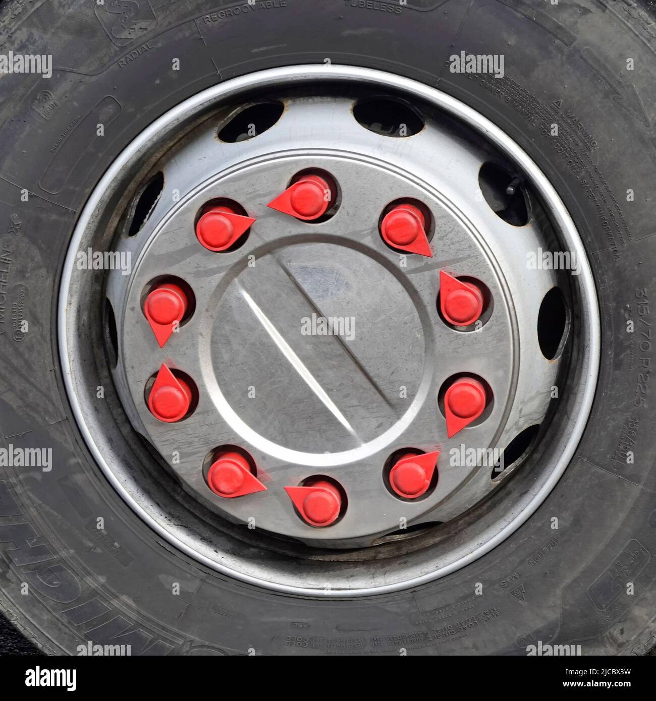 Close up tyre & red loose wheel nut pointed indicator tags road safety device fitted to large HGV lorry truck to give visual defect danger warning UK Stock Photo