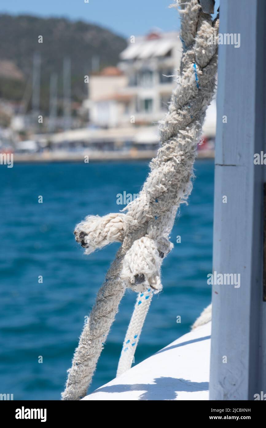 White rope tied to the boat. Mooring ropes on a white boat crossing to an island in Greece Stock