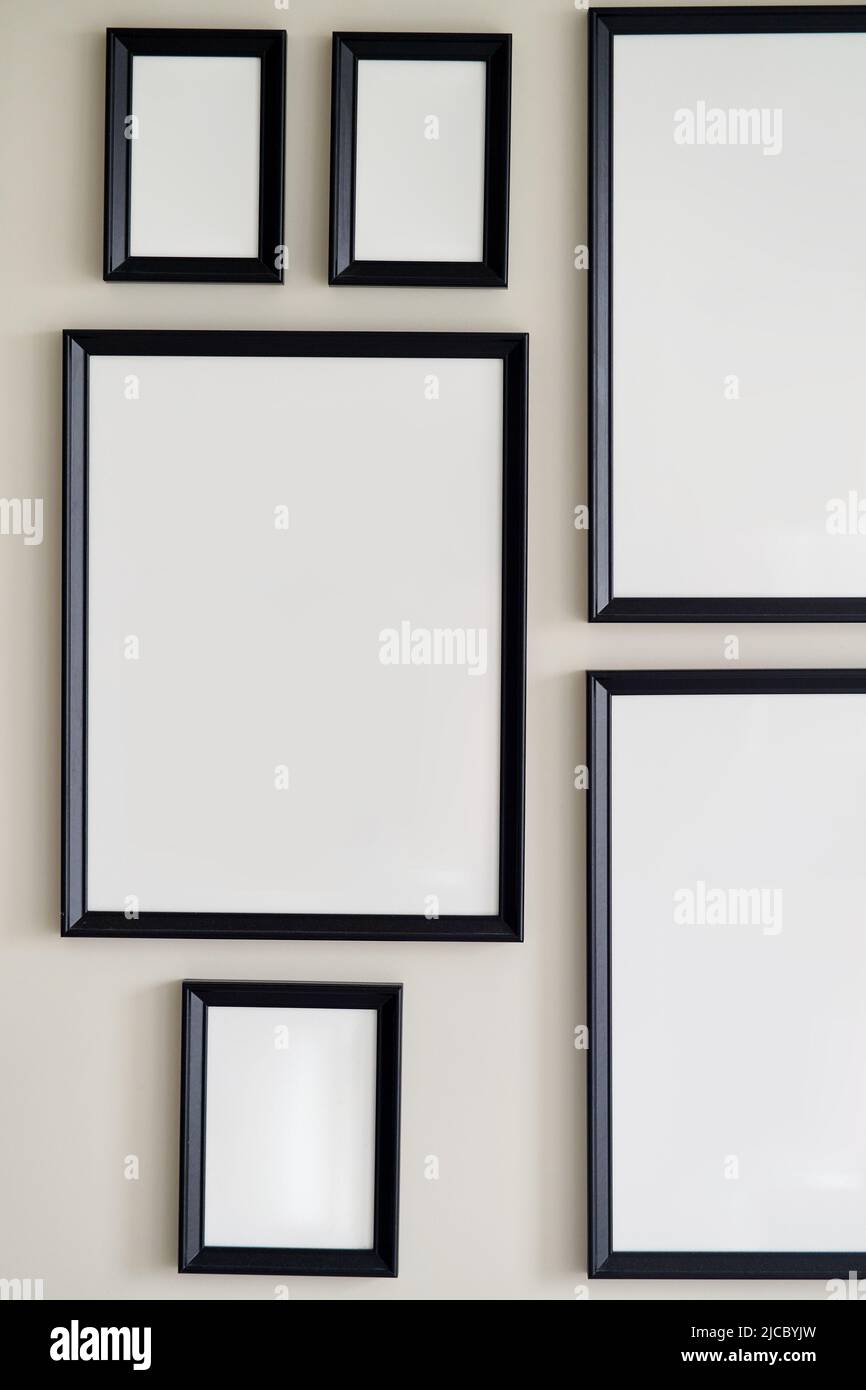 Different size framed photos hanging on the gray wall. Mockup. Stock Photo