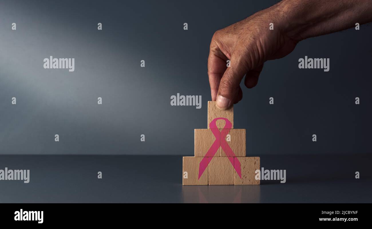 cancer awareness ribbon on wooden blocks on grey blue background , concept of national cancer control  month . Stock Photo