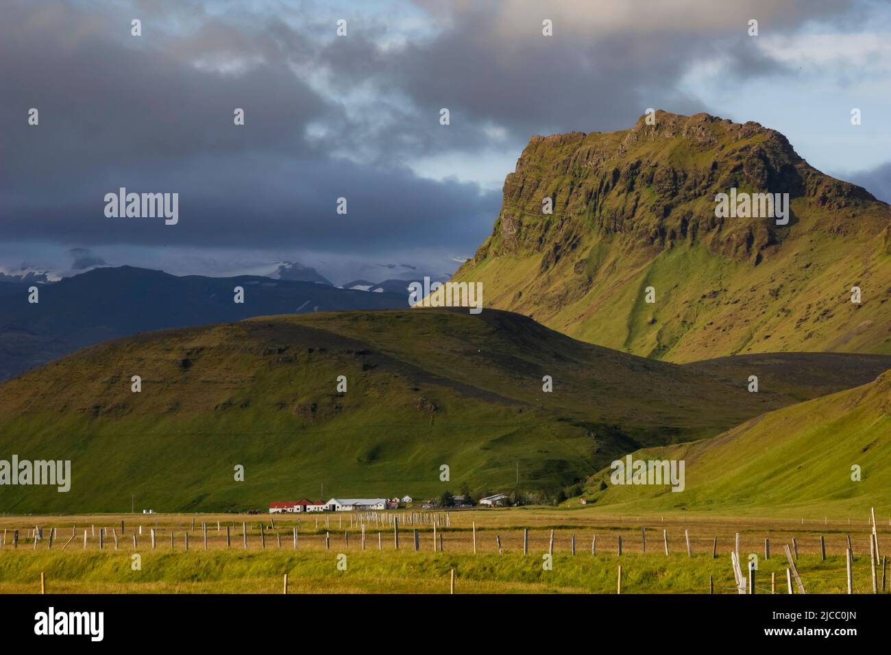 Green mountainscape with farm and fields close to Hringvegur/Route 1 near Vík í Mýrdal, Iceland Stock Photo