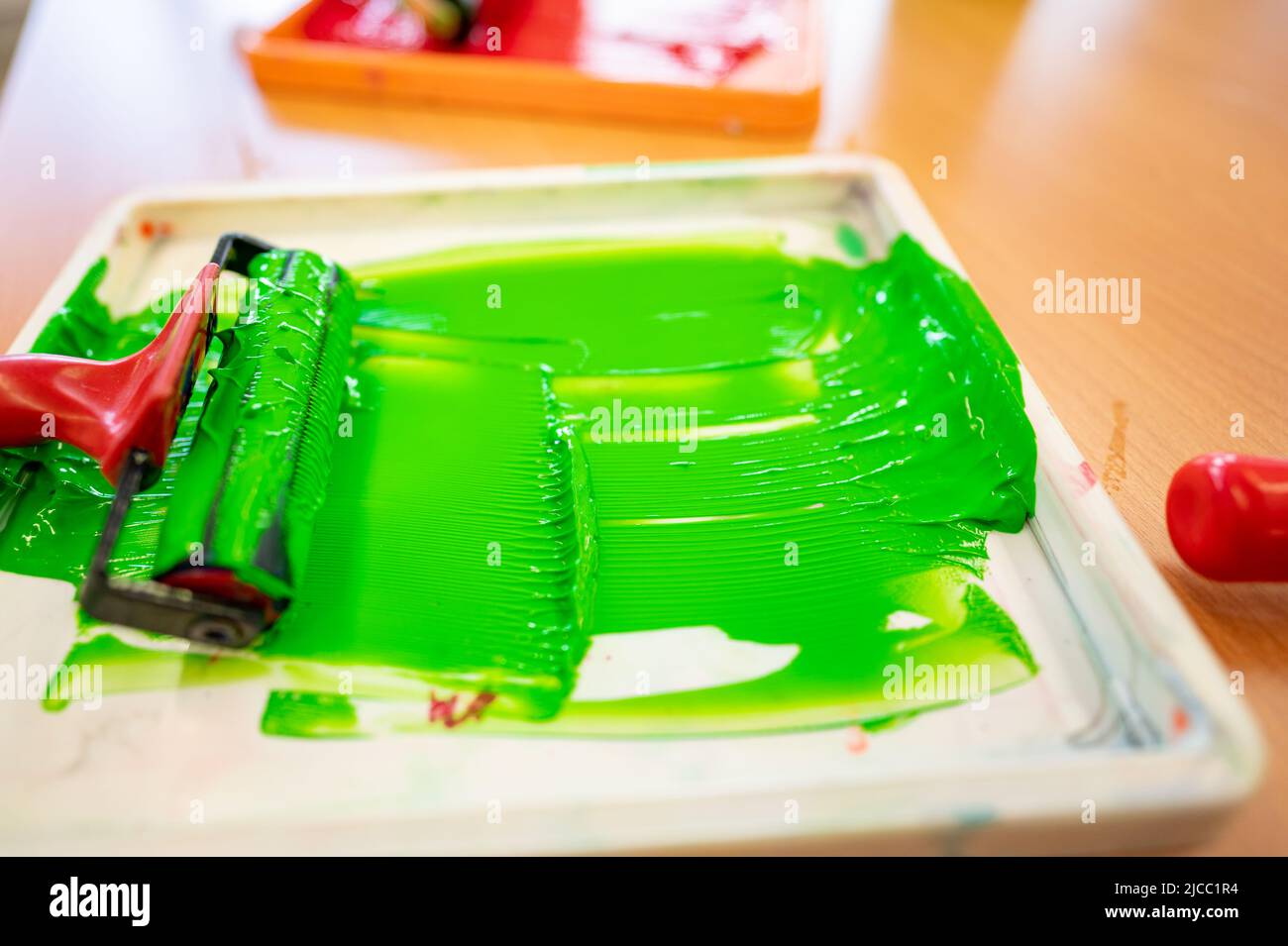 Roll of green paint prepared in a tray in a worker's hand before