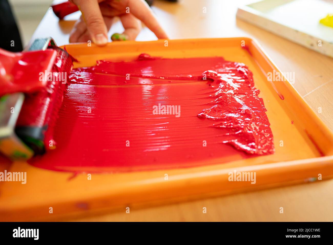 Roll of red paint prepared in a tray in a worker's hand before painting