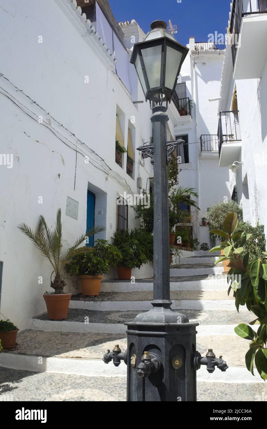 Frigiliana, Spain. A white village in the mountains by the Costa del Sol. Narrow steep alley with flowers in the historic Moorish quarter. Vertical sh Stock Photo