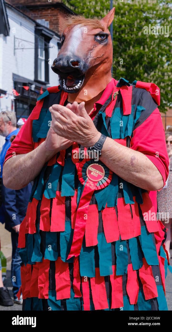 Merrydowners Morris dancer in a tatter coat & horse head claps hands on Pinner High Street at St George’s Day Celebration 2022. Northwest London. Stock Photo
