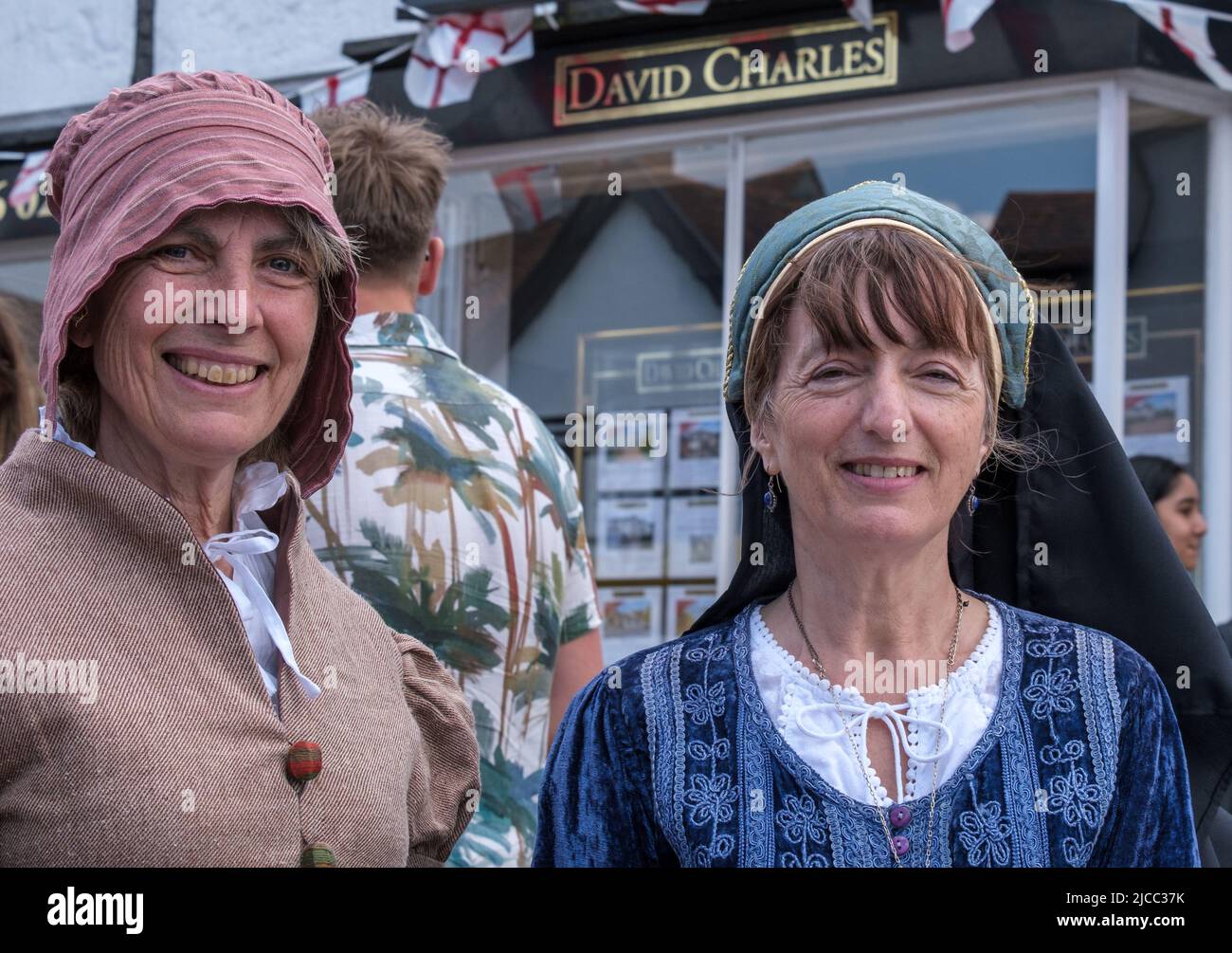 Two ladies from Headstone Manor & Museum in Tudor dress smile during St George’s Day Celebration 2022, Pinner High Street, Harrow, Northwest London. Stock Photo