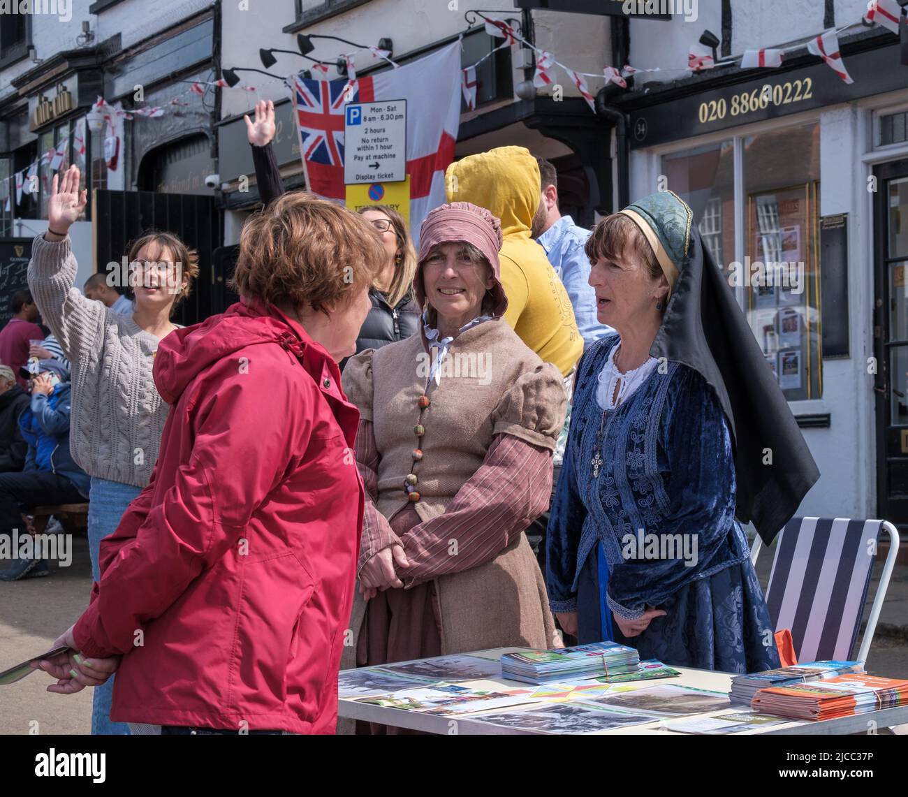 Two ladies in Tudor dress explain about Headstone Manor & Museum next to a table with leaflets at St George’s Day Celebration 2022, Pinner Harrow, UK. Stock Photo