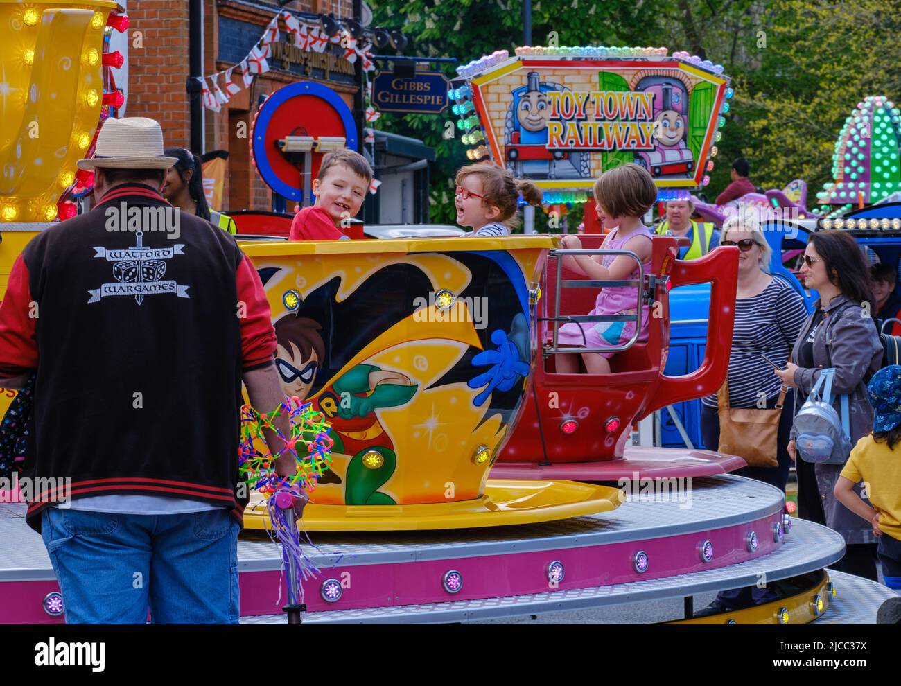 Children enjoy riding in a large teacup street ride while parents look