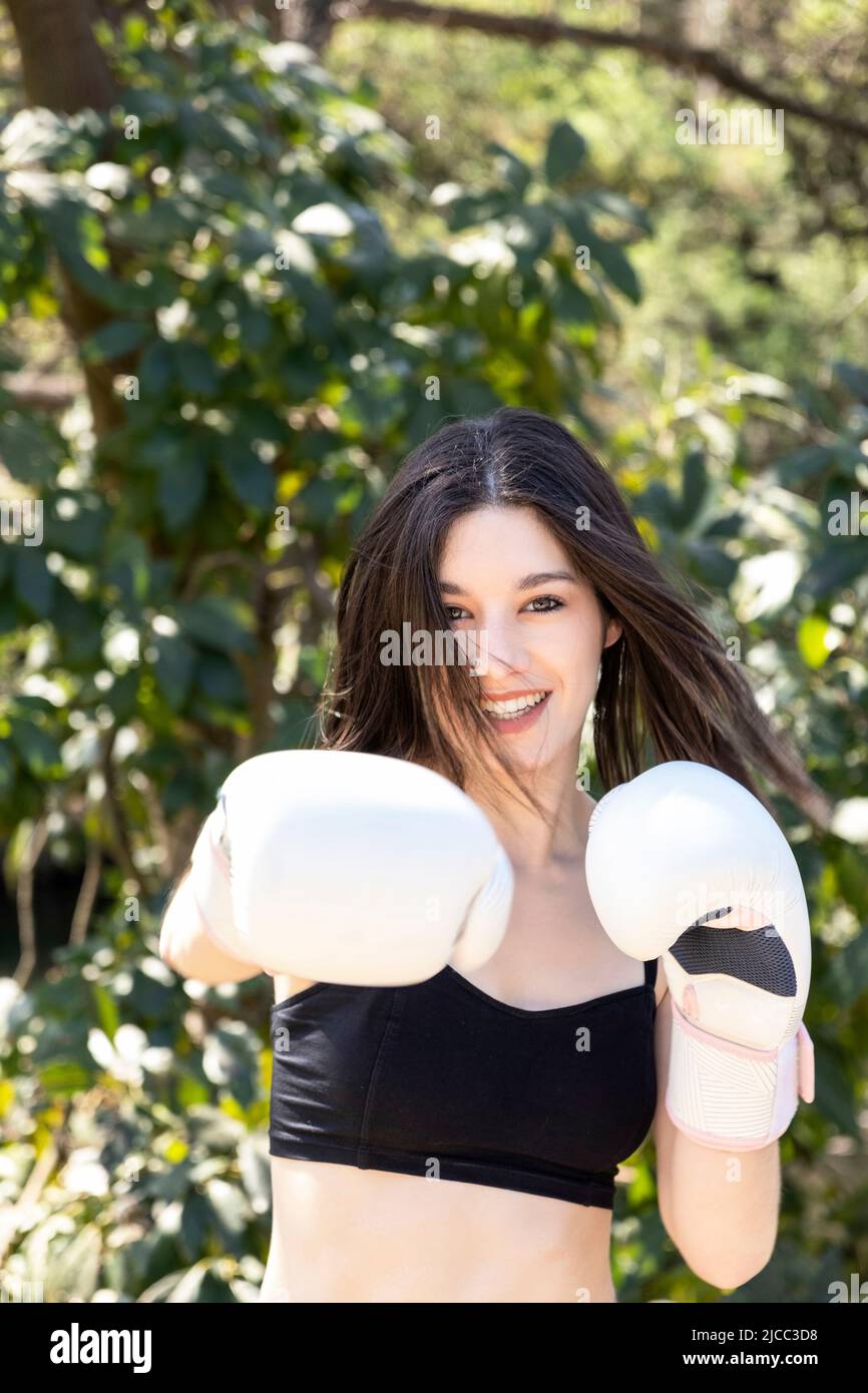 young female boxer with white gloves in a park Stock Photo