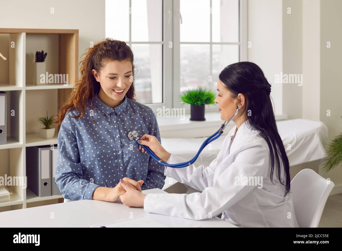Young woman gets her breath or heartbeat examined during checkup at modern clinic Stock Photo