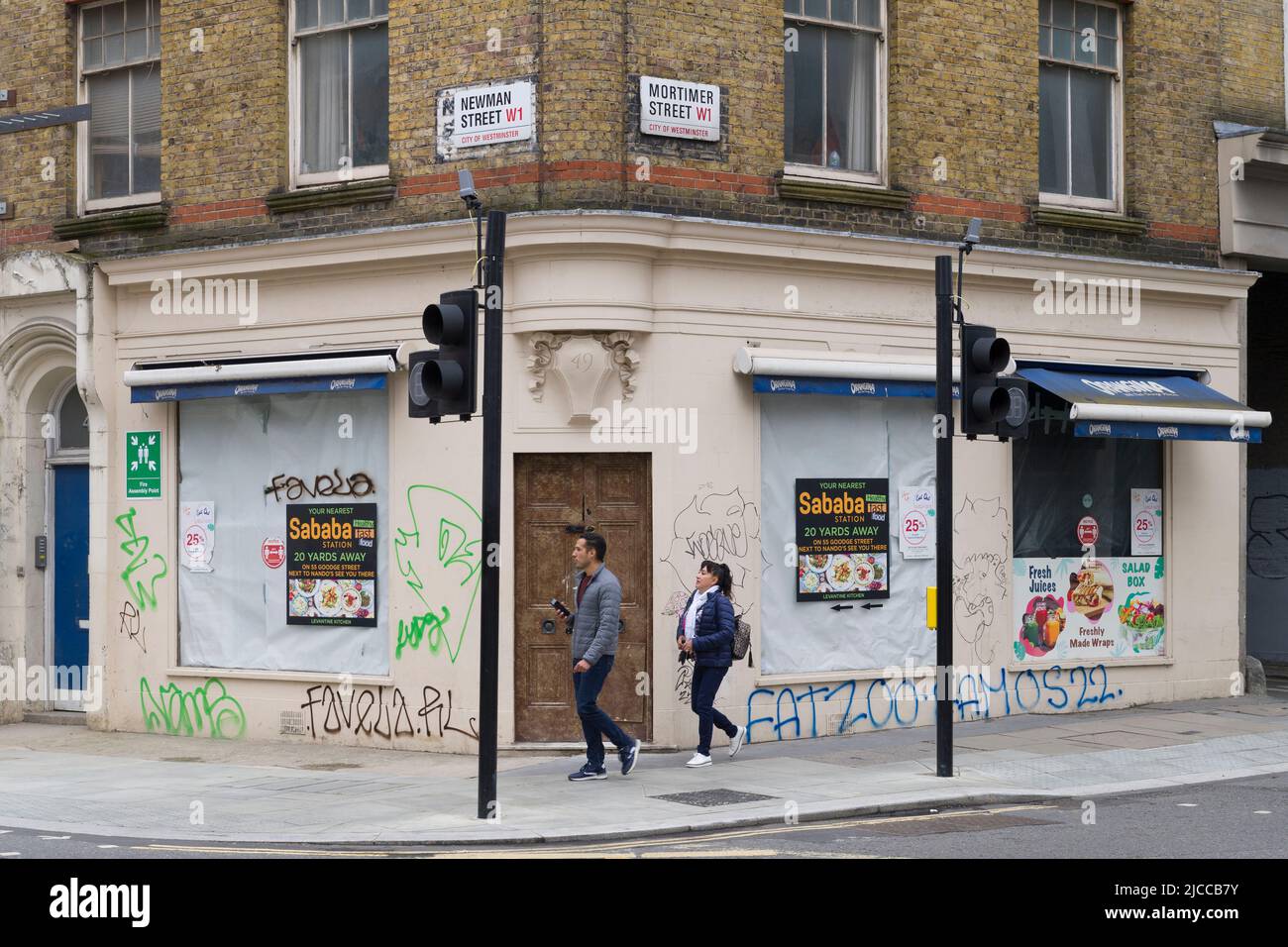 Pedestrians outside closed down and boarded up sandwich shop, Mortimer Street, City of Westminster, London, UK.  5 Jun 2022 Stock Photo
