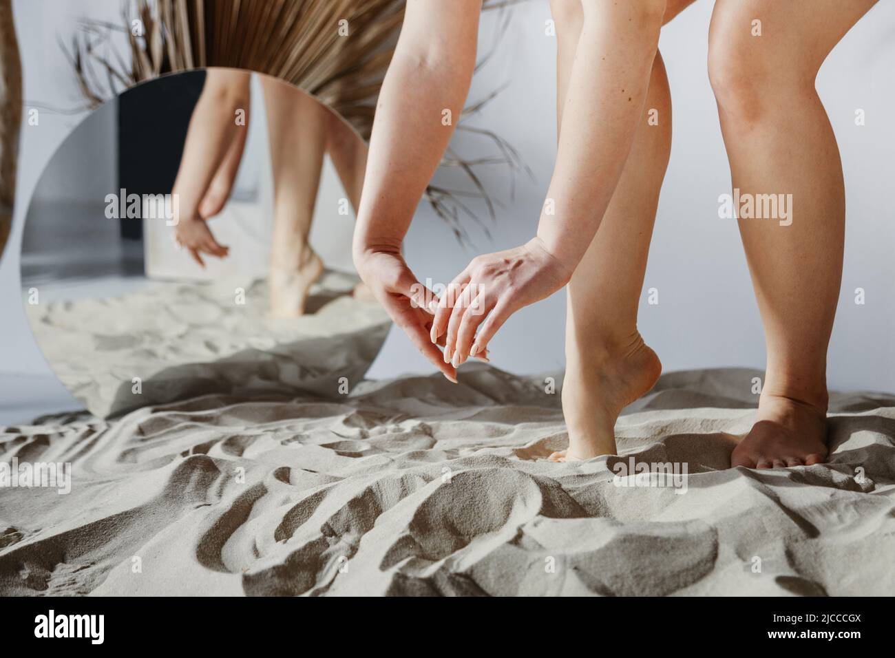 Manicured hands and feet in the mirror reflection. Round mirror in the