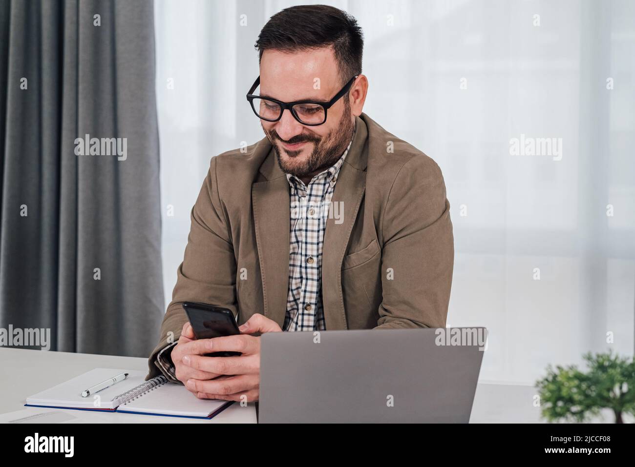 Young smiling business executive messaging online through smart phone ...