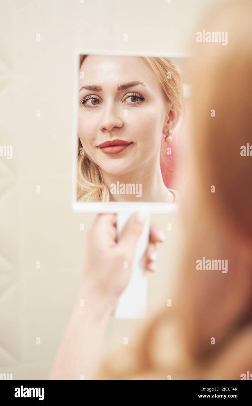 Elegant female reflection in the mirror after the cosmetology procedure