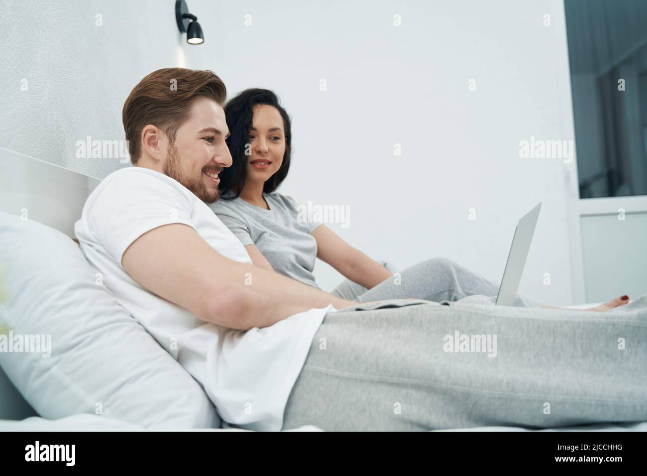 Young couple sitting in bed with laptop Stock Photo